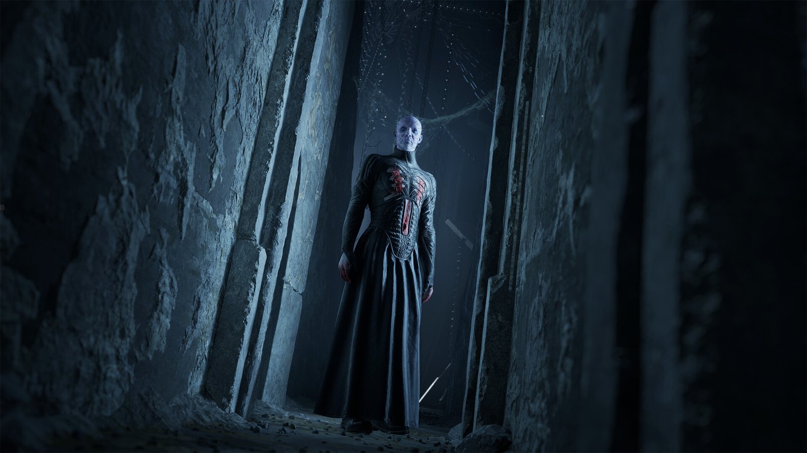 A pale robed figure with a red-lit grille on its chest in a stone corridor